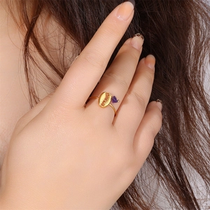 Close-up of gold stainless steel ring with a purple amethyst and coffee bean charm