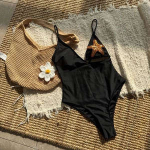 Detail of black one-piece swimsuit featuring gold sequin starfish and thin straps