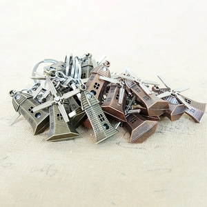 Close-up of vintage metal windmill keychains in bronze and copper finishes on soft fabric