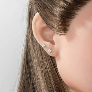 Minimalist silver clover stud earrings featuring a tiny four-bead flower design on model