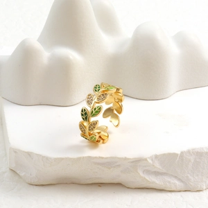 Detailed view of leaf ring with green enamel, gold plating, and tiny zircon accents