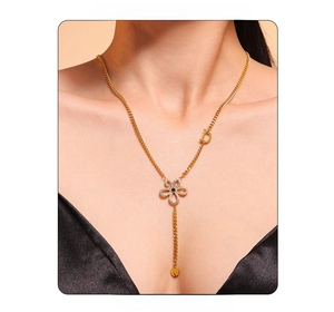 Close-up of gold flower pendant necklace with zircon and D-letter charm on model