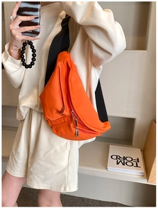 Detail of vibrant orange multi-zipper chest bag with wide nylon strap on display