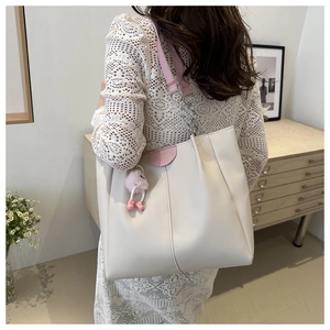 Vista dettagliata di una borsa tote beige con finiture in pelle rosa e catena metallica