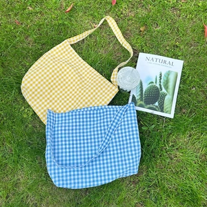 Flat lay of yellow and blue gingham canvas tote bags on a green grass background