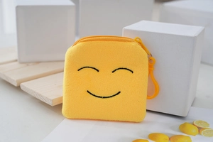 Detailed macro shot of a yellow plush emoji coin purse with zipper and plastic hook