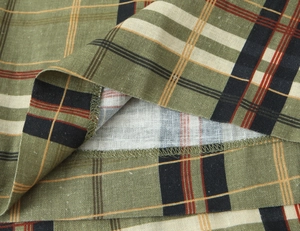 Gros plan sur la texture du lin à carreaux vert olive et les détails de couture d'ourlet
