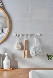 Detail view of wall-mounted stainless steel rack with five hooks and bathroom accessories