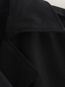 Détail du tissu en sergé noir montrant les coutures précises du revers et de l'épaule