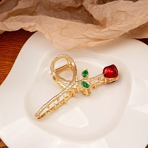 Detail of vintage metal rose hair claw with golden branch texture and red enamel petals