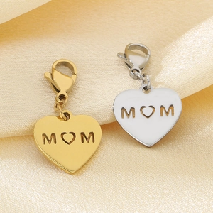 Close-up of gold and silver heart MOM pendants on silk, featuring lobster clasp details