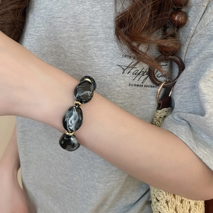 Detailed view of irregular marble resin beads and golden metallic accents on a summer bracelet