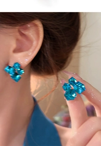 Close-up of blue geometric crystal flower earrings worn by a model with starburst highlights