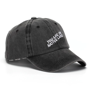 Detail of white embroidered text on washed charcoal cotton baseball cap crown