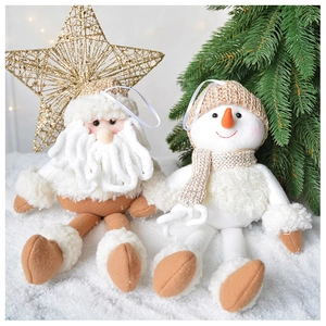 Close-up of plush Santa and Snowman knit ornaments with golden stars on snowy background