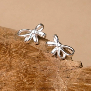 Minimalist 925 sterling silver bow knot stud earrings on a natural wooden display