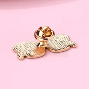 Detailed back view of gold enamel music brooch featuring texture and butterfly clutch pin