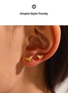 Vue rapprochée de deux boucles d'oreilles cœur en or poli portées sur le lobe de l'oreille