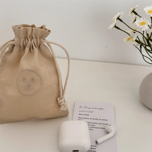 Detailopname van beige linnen tasje met trekkoord en schattig geborduurd gezichtje