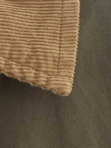 Macro detail of brown corduroy and olive canvas stitching on a casual loose jacket