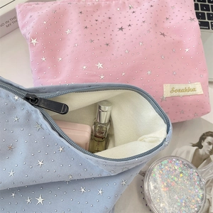 Detail of pink and blue knit makeup bags with silver star sequins and perfume inside