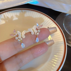 Elegant butterfly drop earrings with pearls and crystals held on fingertips