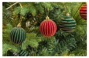 Close-up of velvet Christmas ornaments with gold glitter stripes on pine tree branches