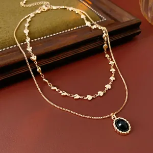 Double-layered gold-plated necklace with heart chain and black oval gemstone pendant