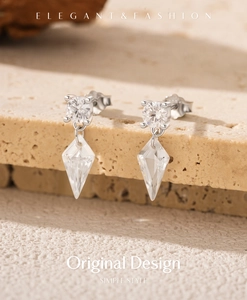 Close-up of S925 silver drop earrings with kite-shaped crystal on stone background