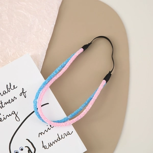 Detail of pink and blue glitter headbands with black elastic bands on a beige display mat