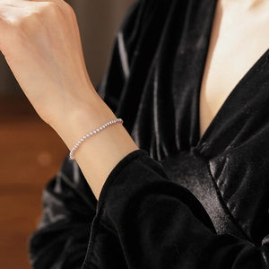 Close-up of elegant pearl beaded bracelet on model wrist with black velvet sleeve