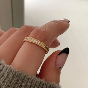 Detailed macro view of a gold double-row zircon ring featuring micro-pave setting on finger