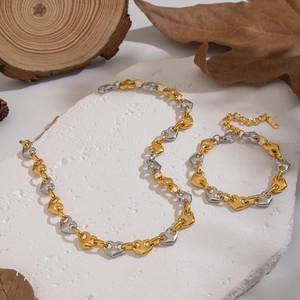 Two-tone stainless steel heart chain necklace and bracelet jewelry set on rustic wood