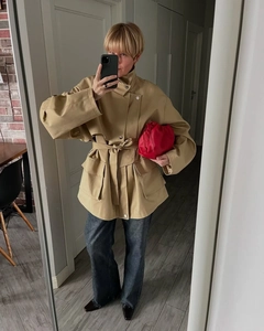 Close-up of khaki trench coat detail showing large side pockets and waist belt tie