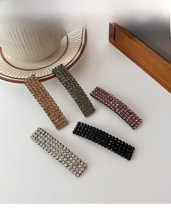 Close-up of sparkling rhinestone hair clips in five colors on a minimal white surface
