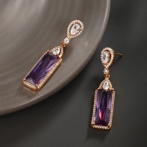 Détail de boucles d'oreilles avec cristal violet rectangulaire et plaqué or rose