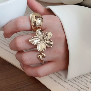 Macro shot of a golden metal flower ring with textured petals on a woman's hand