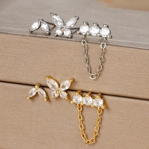 Macro shot of silver and gold butterfly earring sets with zircon chains and metal texture