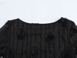 Gros plan sur une robe noire élégante avec fleurs 3D et texture à rayures verticales