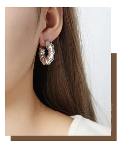 Macro detail of silver tone C-shape bamboo style earring on model with metallic finish