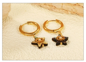 Macro detail of gold star earrings with abalone shell inlay and evil eye crystal