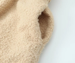 Detailed macro view of the fuzzy beige sherpa wool texture and stitched pocket seam
