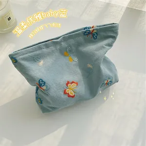 Close-up of embroidered butterfly and flower details on light blue fabric makeup bag