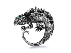 Detail of silver lizard brooch with textured scales and black gemstone inlay