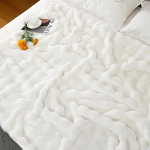 Close-up of white faux fur blanket with soft texture on a bed with decor accessories