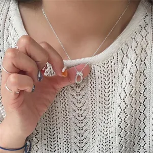 Close-up of minimalist S925 sterling silver knot necklace worn on neck
