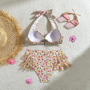 Détail de bikini à fleurs avec culotte haute à volants sur fond blanc en peluche