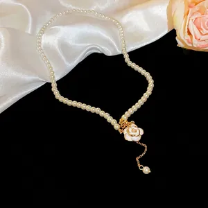 Elegant camellia pearl pendant necklace with gold chain on white silk background