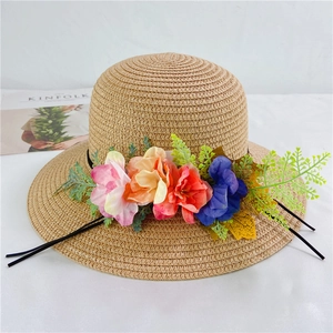 Detail view of khaki straw hat with colorful fabric flowers and Kinfolk magazine background