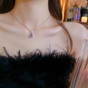 Close-up of a purple gourd-shaped zircon necklace on model wearing black feather dress